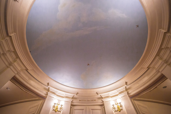 Mit blassblauem Himmel, weißen Wolken und kleinen Vögeln bemalte Decke vor dem Mittelbalkon im Foyer der Semperoper