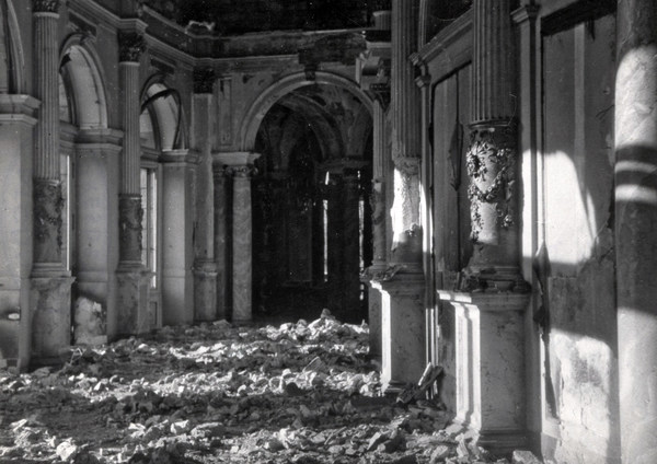 Rundfoyer der zerstörten Semperoper mit Blick auf einen Torbogen, rechts und links sind Säulen zu sehen, der Fußboden ist mit Schutt bedeckt